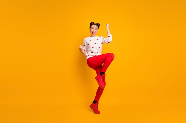 キューピッドの女性の全身写真は、ロマンチックな日付の招待状を祝う片足で拳を上げるハートパターン白いセーター赤いズボンの靴