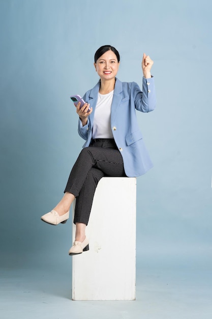 full body photo of an elderly businesswoman using a smartphone