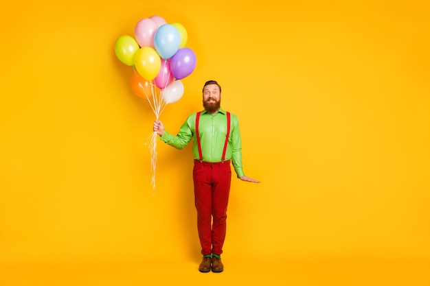 Full body photo of imposing man hold many balloons celebrate b-day event wear good look outfit isolated over vibrant color