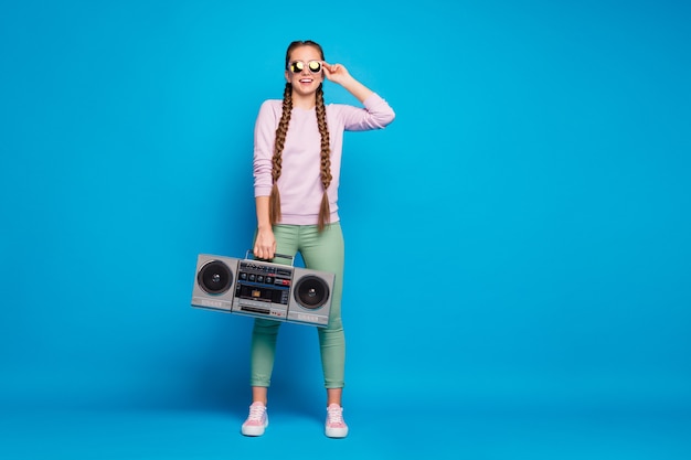 Full body photo of modern youth with braids pigtails girl hold retro boombox feel crazy want party on spring holidays wear pink sweater sneakers green pants trousers isolated blue color background