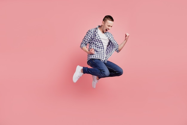 Full body photo of young guy happy positive smile jumping celebrate victory lucky isolated on pink color background