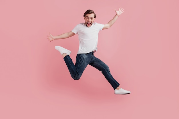 Foto completa del corpo di un giovane uomo positivo sorridente eccitato felice che salta su attivo isolato su sfondo di colore rosa