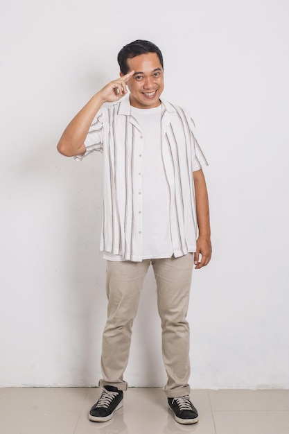 Full body portrait of cheerful handsome asian man saluting with two fingers