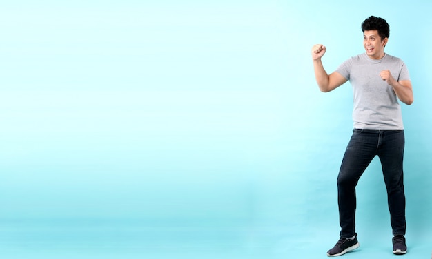Full body Portrait of handsome Asian man Happy excited raising his fists doing yes gesture celebrating success. isolated   in studio With copy space.