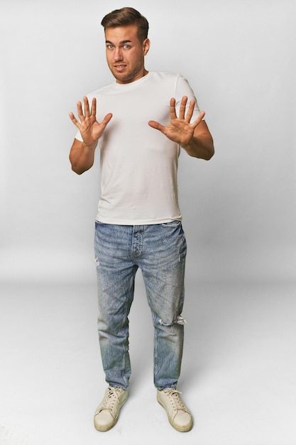 Full body portrait of a man in studio rejecting someone showing a gesture of disgust