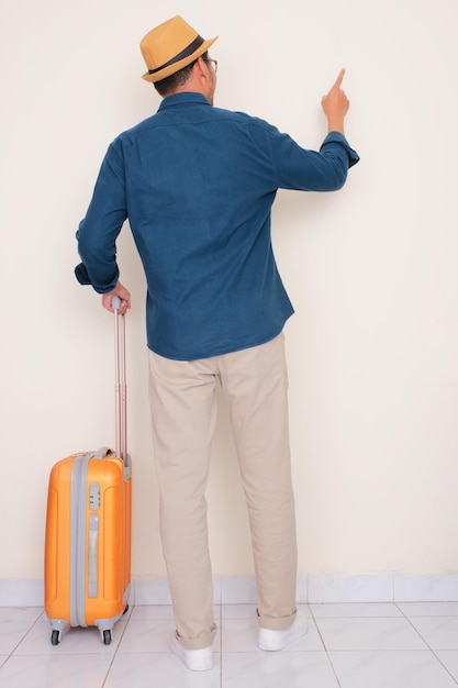 Photo full body portrait of a man with suitcase pointing to something back view