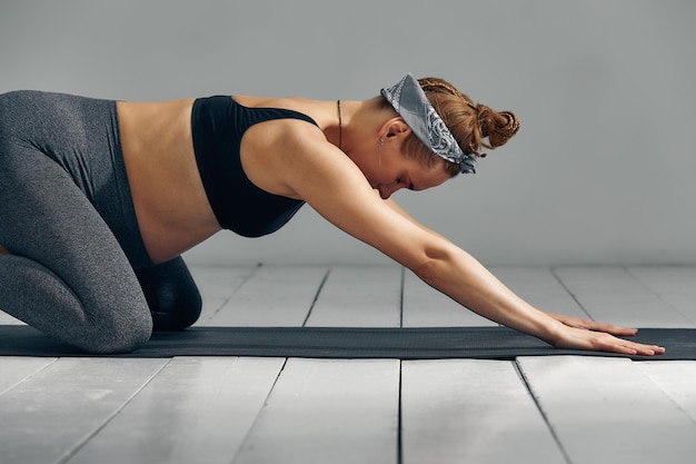 Full Body Portrait Of Pregnant Woman Doing Yoga On Exercise Mat Isolated on gray background