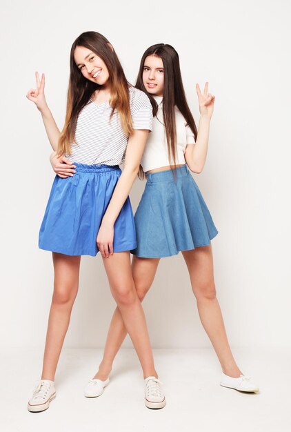 Full body portrait of two happy girls over white background