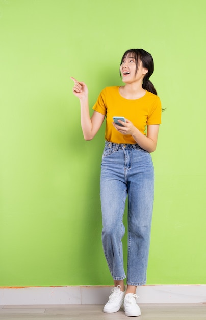 Full body portrait of young asian girl on green wall