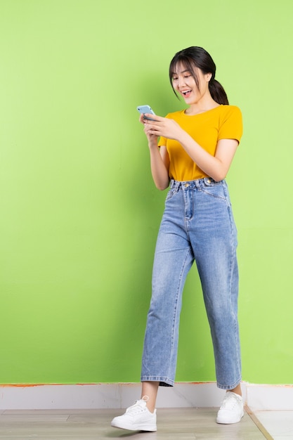 Full body portrait of young asian girl on green wall
