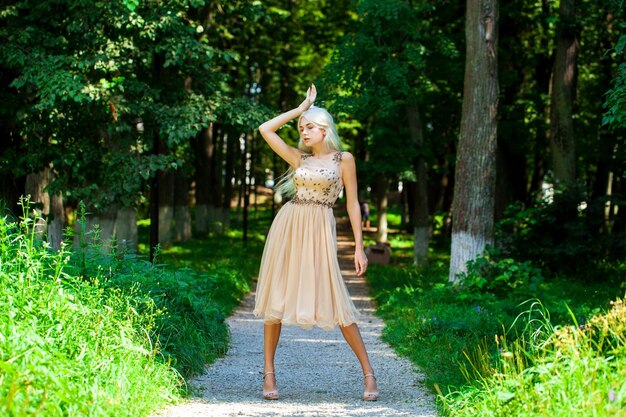 Photo full body portrait of a young beautiful blonde woman in beige dress summer park outdoor