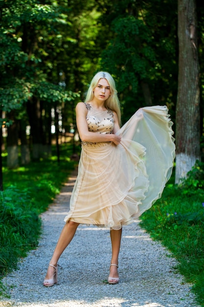 Photo full body portrait of a young beautiful blonde woman in beige dress summer park outdoor