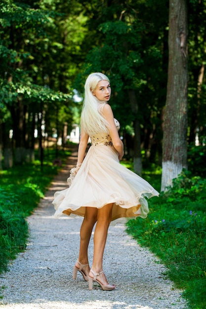 Photo full body portrait of a young beautiful blonde woman in beige dress summer park outdoor