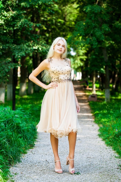 Photo full body portrait of a young beautiful blonde woman in beige dress summer park outdoor