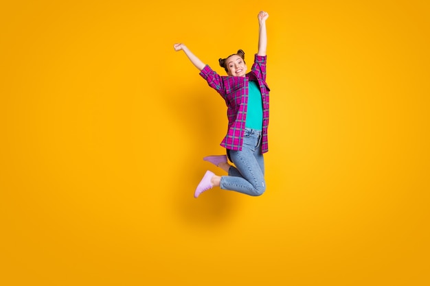 Full body profile photo of crazy teen lady jump high up air flight champion sports competition overjoyed wear casual plaid shirt shoes sneakers jeans isolated yellow color background