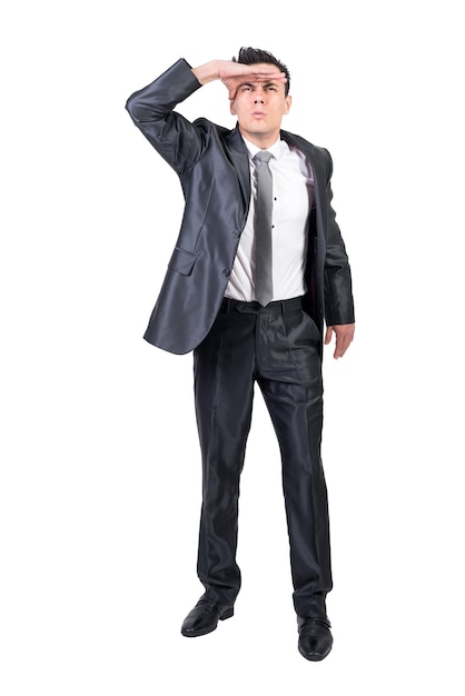 Full body of serious observant male in formal suit looking away with hand at forehead isolated on white background in studio