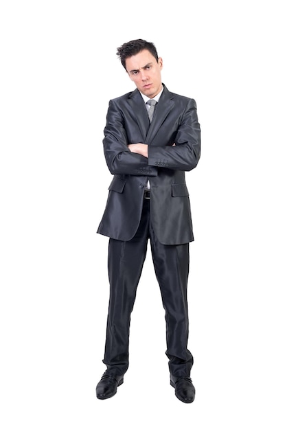 Full body of serious young male manager with dark hair in formal clothes looking at camera while standing against white background with crossed arms