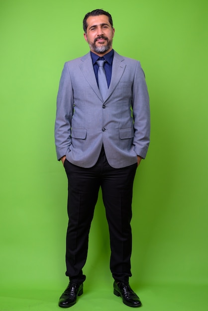 Full body shot of handsome Persian bearded businessman on green