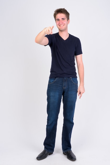 Full body shot of happy young handsome man pointing at camera