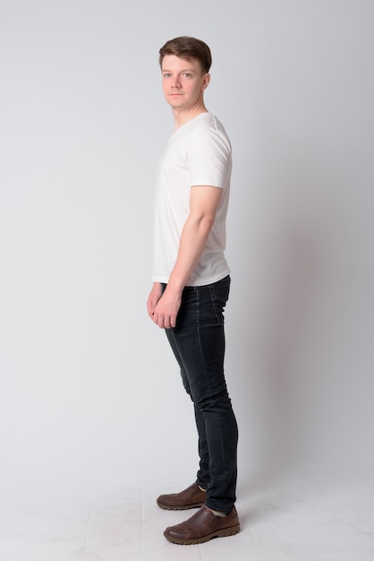 Full body shot profile view of young handsome man looking at camera