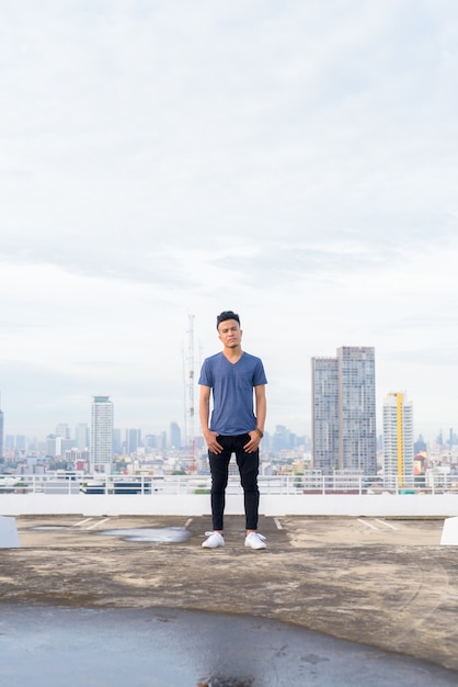 Full body shot of young handsome multi ethnic man against view of the city