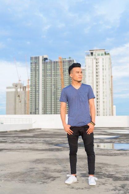 Full body shot of young handsome multi ethnic man thinking against view of the city