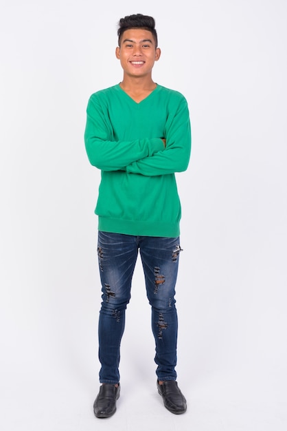 Full body shot of young happy Asian man with arms crossed