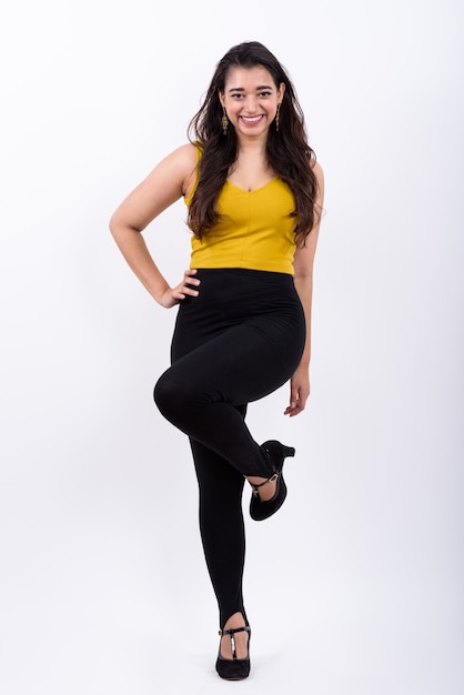 Full body shot of young happy Indian woman smiling with hand on