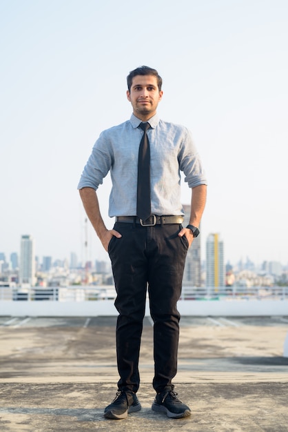 Full body shot of young Persian businessman against view of the city