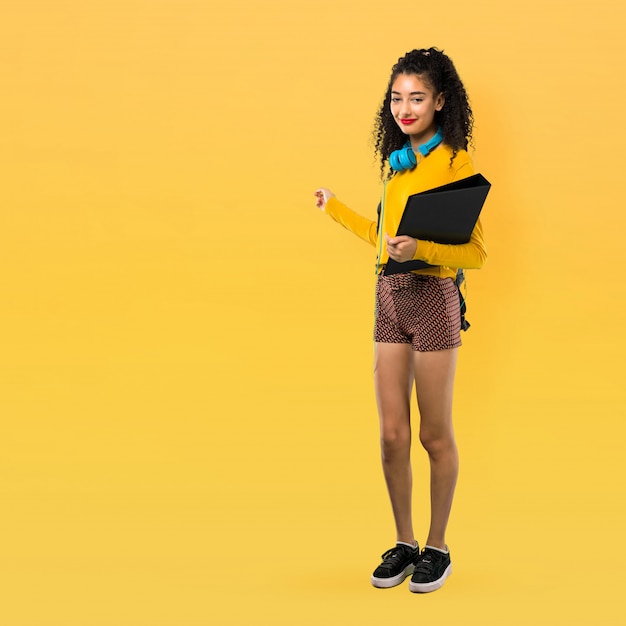 Full body of Teenager student girl with curly hair pointing back with the index finger