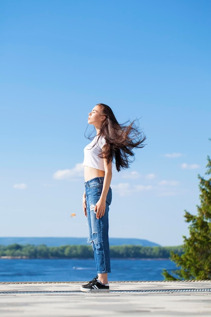 Full body young beautiful brunette woman posing against blue sky bright sunny weather