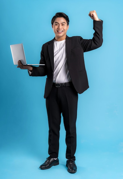 Full body Young business man wearing a vest using laptop and posing on a blue background