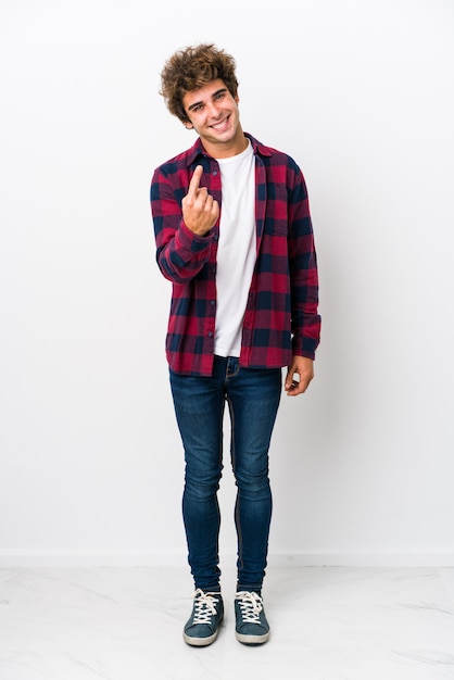 Full body young caucasian man isolated pointing with finger at you as if inviting come closer.