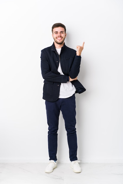 Full body young caucasian man isolated smiling cheerfully pointing with forefinger away.