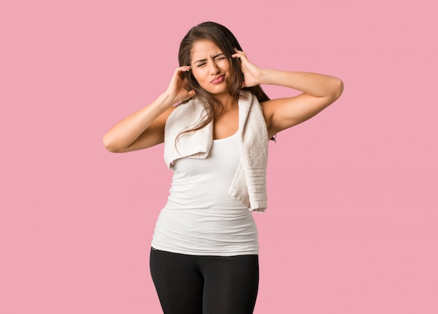 Full body young fitness curvy woman covering ears with hands