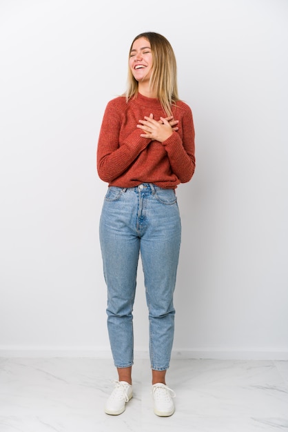 Giovane donna dell'ente completo che ride tenendo le mani sul cuore