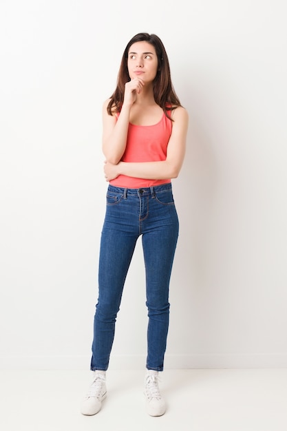 Full body young woman on white background with doubtful and skeptical expression