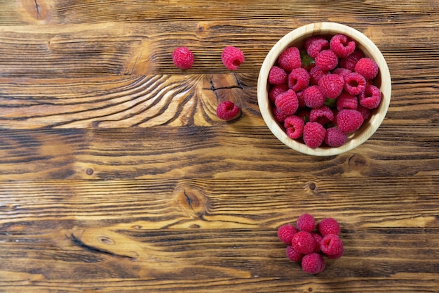 Full bowl of raspberries on wooden table