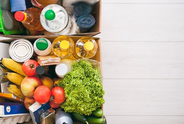 The full cardboard eco box with products from the grocery store\
on the floor at home