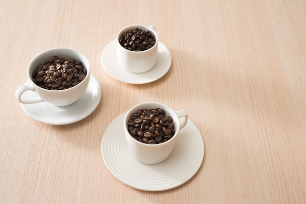 Full coffee beans cups on the wood surface