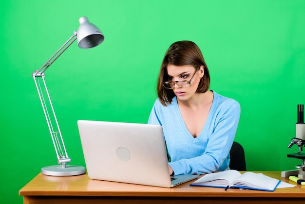 Full concentration at work concentrated secretary at workplace chemist biologist with microscope on table digital science businesswoman data Business woman woman work in office on laptop