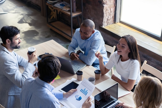 Full concentration at work. Group of young business people working and communicating while sitting at the office desk together with colleagues sitting in the background.