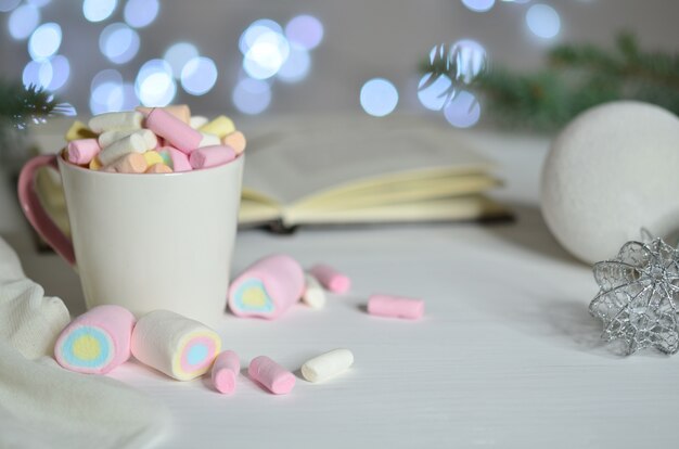 Tazza piena di marshmallow colorati e palla di natale su sfondo bokeh