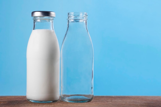 Foto bottiglia piena e vuota di latte su uno sfondo blu di prodotti lattiero-caseari