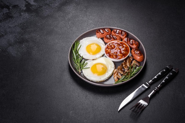 Full english breakfast bean fried eggs roasted sausages tomatoes mushrooms on a dark concrete table with toasted bread