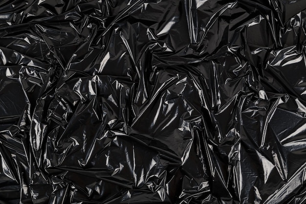 Full frame abstract background of crumpled black plastic film\
bag