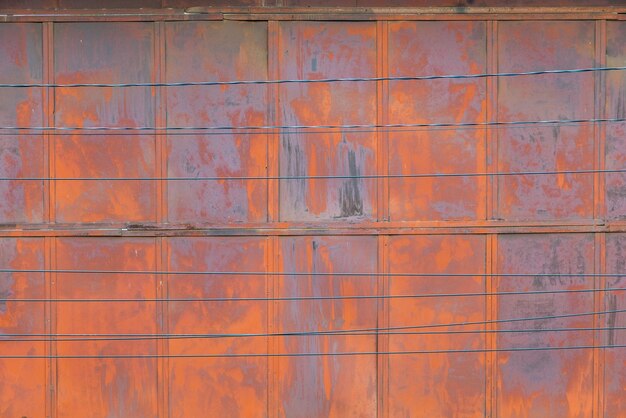 Full frame background and texture of rusted steel sheet wall and horiozntal wires in front of it