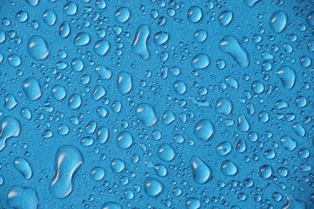 Full-frame opname van regendruppels op het blauwe raam