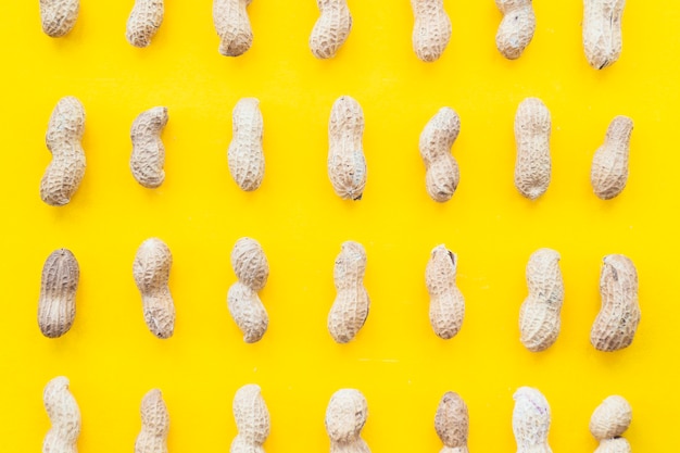 Full frame of raw whole peanuts on yellow backdrop