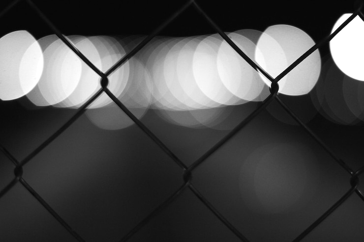 Photo full frame shot of chainlink fence against illuminated electric lights